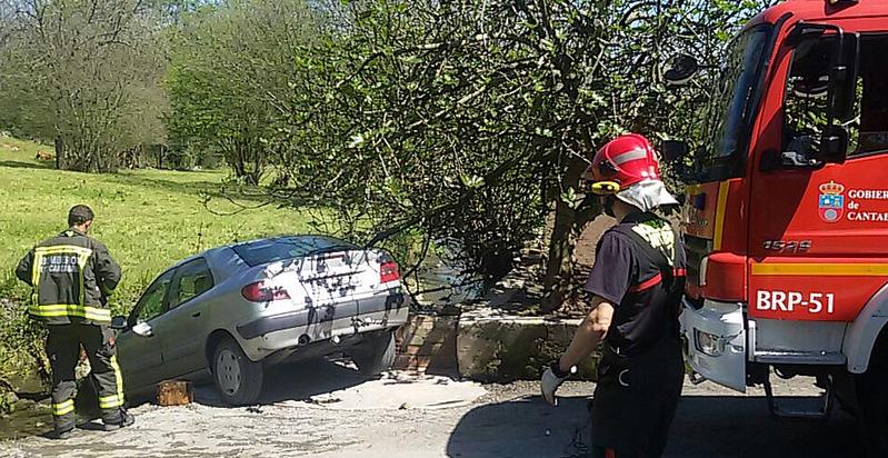 Los bomberos liberan a un hombre atrapado entre su vehículo y una roca del cauce de un riachuelo